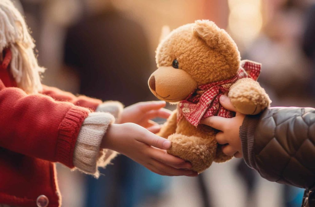 Poignant image of a child's hand receiving a teddy bear at a charity event, shallow depth of field, vibrant colors